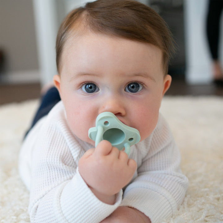 https://cdn.shopify.com/s/files/1/0659/5860/9120/products/PS12007_Lifestyle_HappyPaci_Silicone_Pacifier_Green_O16A1675.jpg?v=1661693222